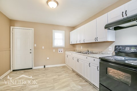 A kitchen with white cabinets and a black stove top oven.