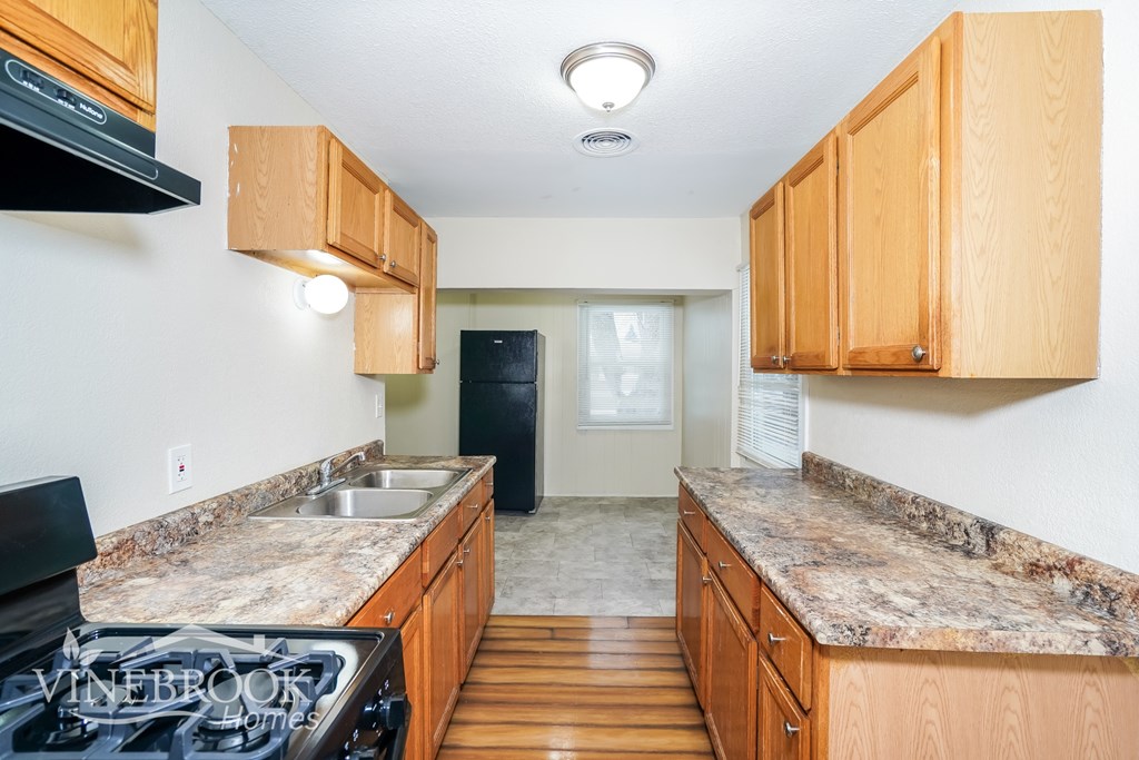 A kitchen with wooden cabinets and a black stove top.