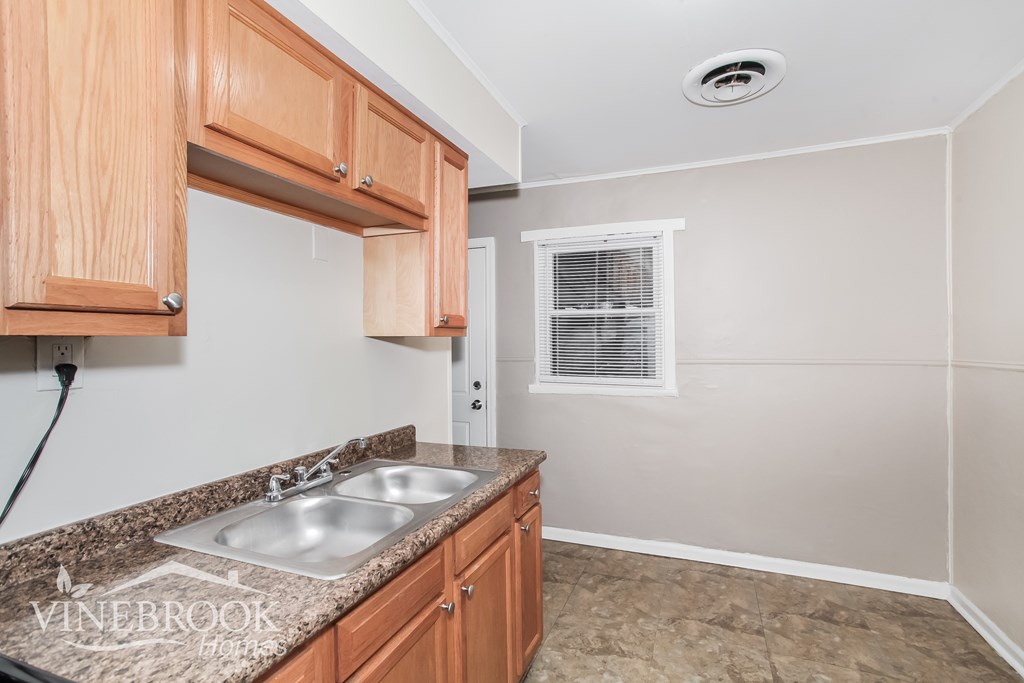 A kitchen with wooden cabinets and a granite countertop.