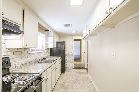 A kitchen with a stove top oven and a refrigerator.