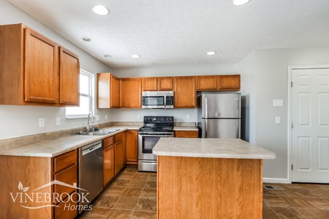 A kitchen with wooden cabinets and a Vinebrook Homes logo.
