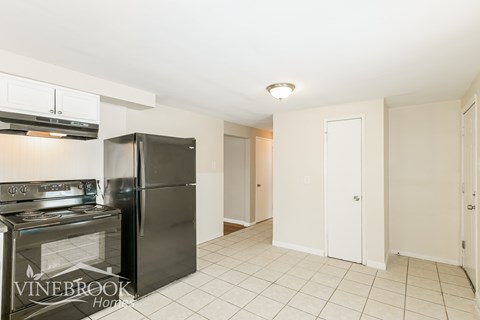 A kitchen with a black refrigerator and stove top oven.