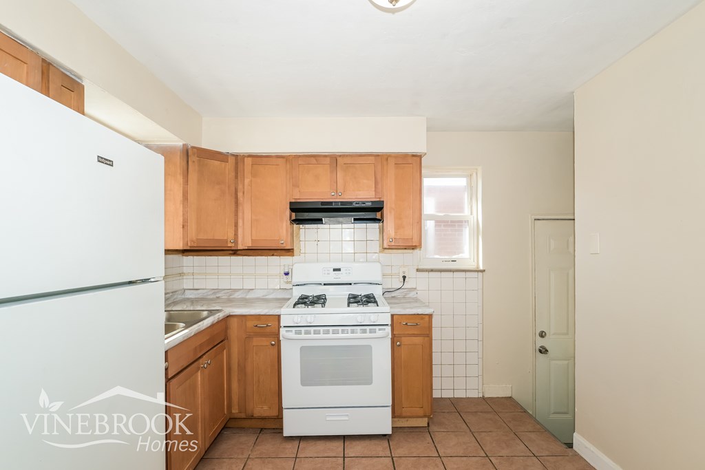 A kitchen with wooden cabinets and a white fridge.