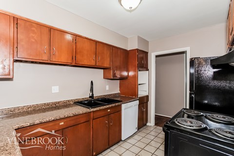 A kitchen with brown cabinets and a black stove.
