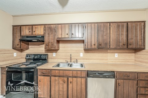 A kitchen with wooden cabinets and a stove top oven.