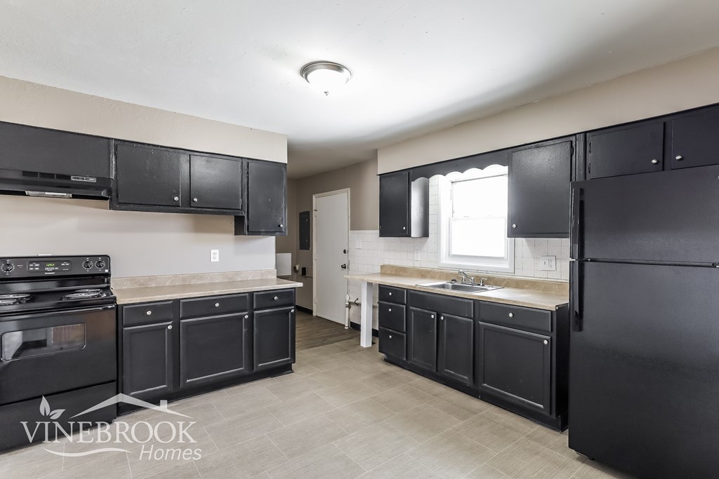 A kitchen with black cabinets and appliances is shown.