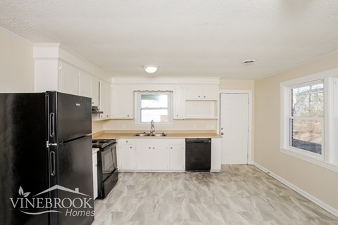 A kitchen with a black fridge and white cabinets.