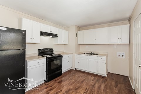 A kitchen with black appliances and white cabinets.