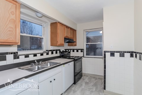 A kitchen with white cabinets and black countertops.