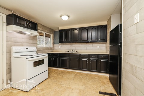A kitchen with black cabinets and a white stove.