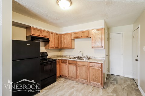 A kitchen with wooden cabinets and a black fridge.