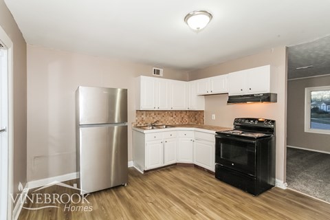 A kitchen with a stainless steel refrigerator and black oven.