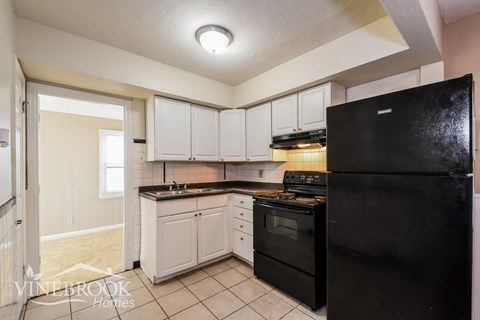 A kitchen with a black refrigerator and white cabinets.