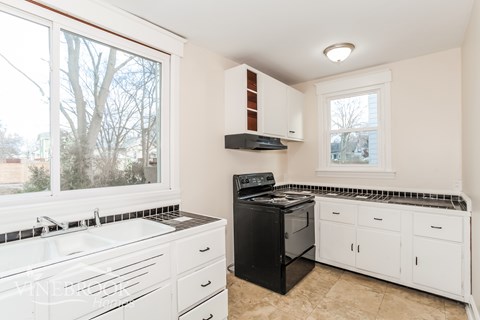 A black stove in a white kitchen with a window.
