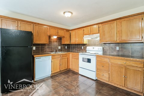 A kitchen with wooden cabinets and a black refrigerator.