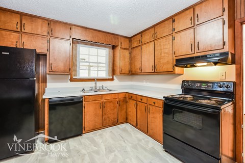 A kitchen with wooden cabinets and black appliances.