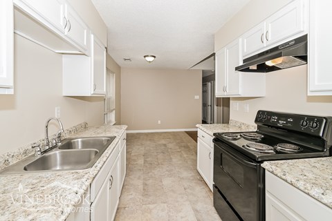 A kitchen with a black stove top oven and a marble counter top.
