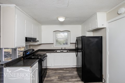 A kitchen with black appliances and white cabinets.