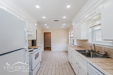 A kitchen with white cabinets and a black fridge.