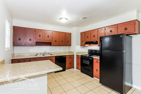 A kitchen with brown cabinets and a black refrigerator.