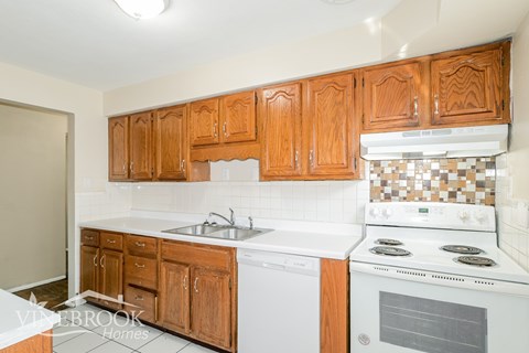A kitchen with wooden cabinets and a white stove top oven.