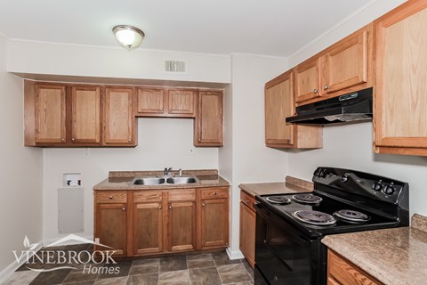 A kitchen with wooden cabinets and a black stove top oven.
