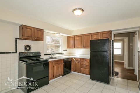 A kitchen with black appliances and wooden cabinets.