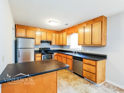 A kitchen with wooden cabinets and a black countertop.