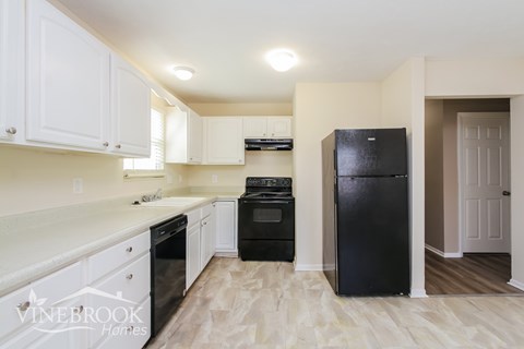 A kitchen with white cabinets and black appliances.