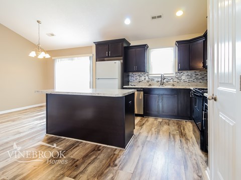 A kitchen with dark wood cabinets and a white fridge.