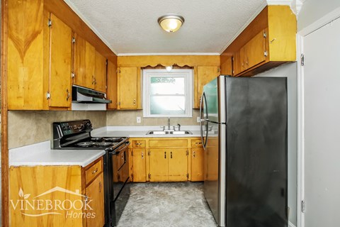 A kitchen with wooden cabinets and a black refrigerator.