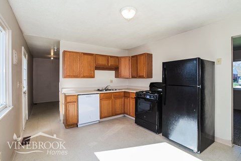A kitchen with black appliances and wooden cabinets.