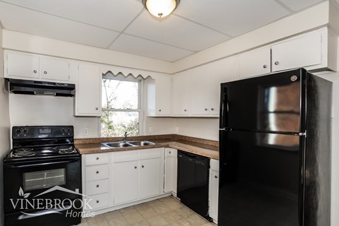A kitchen with white cabinets and black appliances.