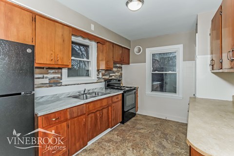 A kitchen with wooden cabinets and a black refrigerator.