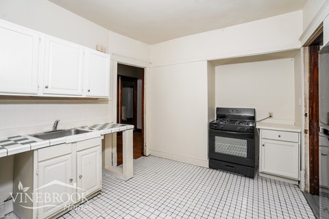 A kitchen with white cabinets and a black and white checkered floor.