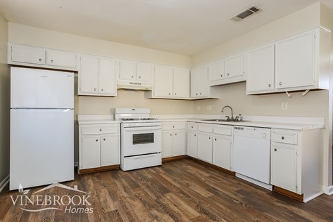 A kitchen with white cabinets and a white fridge.