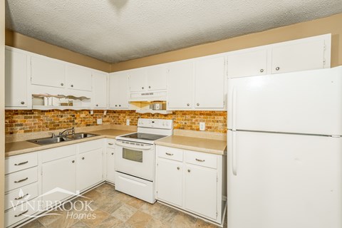 A kitchen with white cabinets and a brick backsplash.