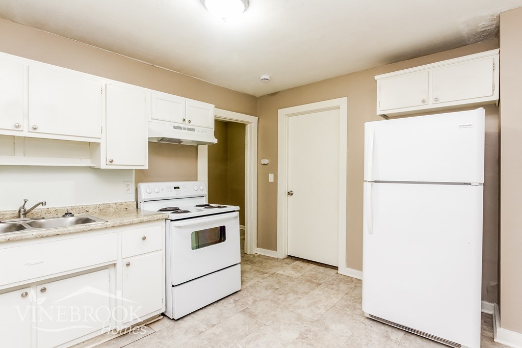A kitchen with white appliances and cabinets.