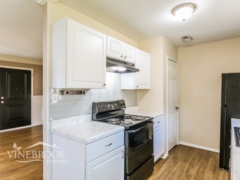 A kitchen with white cabinets and a black stove top oven.
