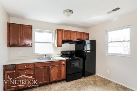 A kitchen with black appliances and wooden cabinets.