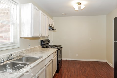 A kitchen with white cabinets and a black refrigerator.
