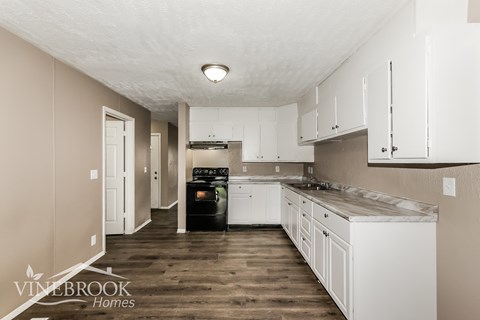 A kitchen with white cabinets and a wooden floor.