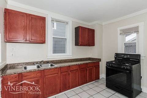 A kitchen with red cabinets and a black stove.