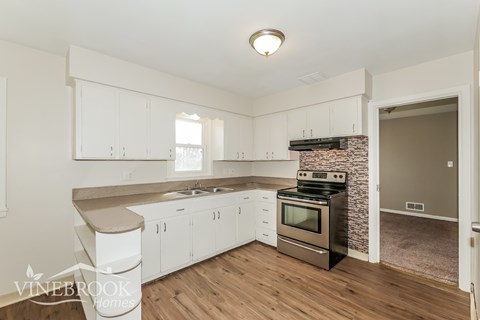 A kitchen with white cabinets and a stone backsplash.