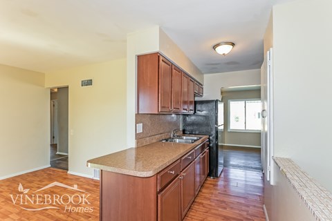 A kitchen with wooden cabinets and a black refrigerator.