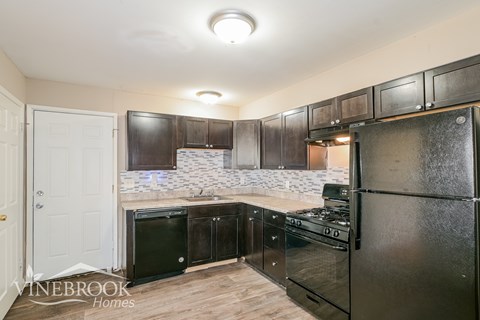 A kitchen with black cabinets and appliances.