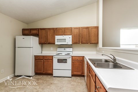 A kitchen with white appliances and wooden cabinets.