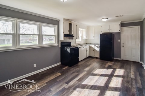 A kitchen with a black fridge and stove in a house.