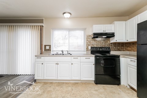A kitchen with white cabinets and black appliances.