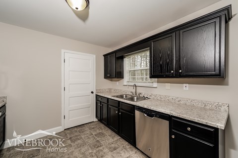 A kitchen with black cabinets and a white door.